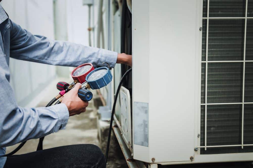 Technician checking AC refrigerant with gauges