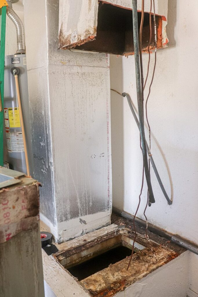 Before AC replacement: old air handler removed, showing a rusted, water-damaged platform and loose lines